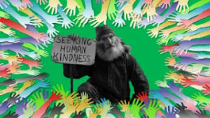 The image shows many hands surrounding a man holding a sign saying "Seeking Human Kindness".